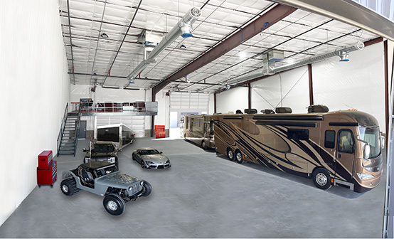 Image of a large garage housing two large RV's to the right and some vehicles off to the left.